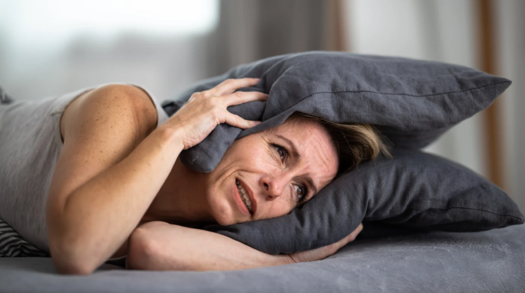 woman covering her ears with a pillow