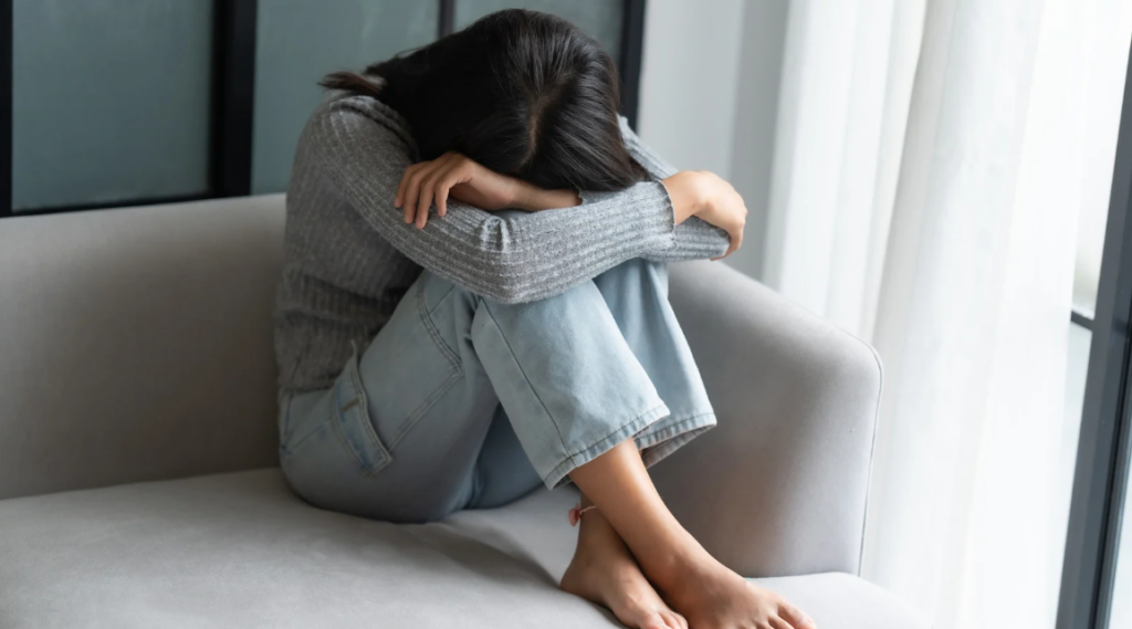 woman feels sad sitting on the couch