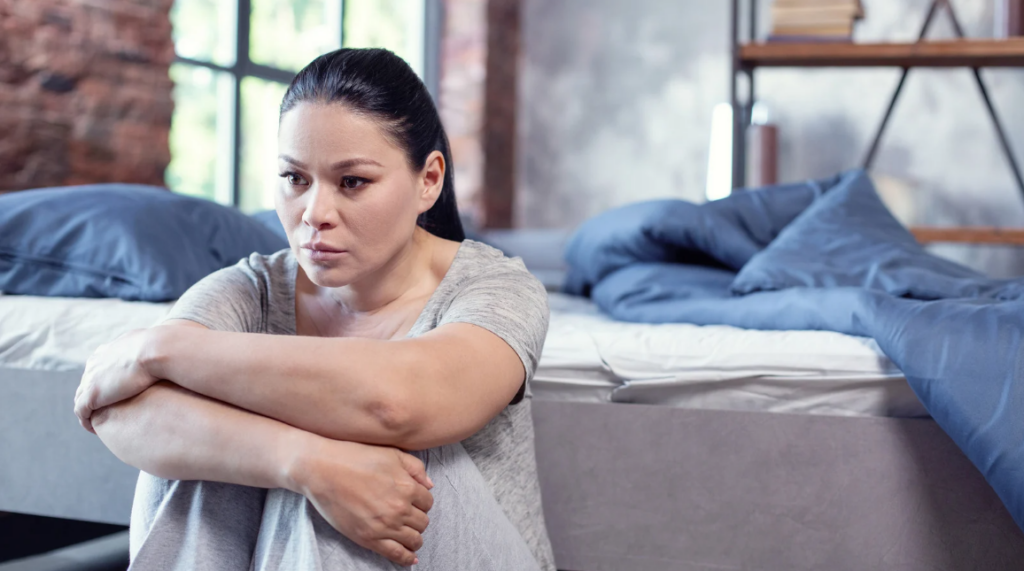 woman sitting beside the bed showing irritability
